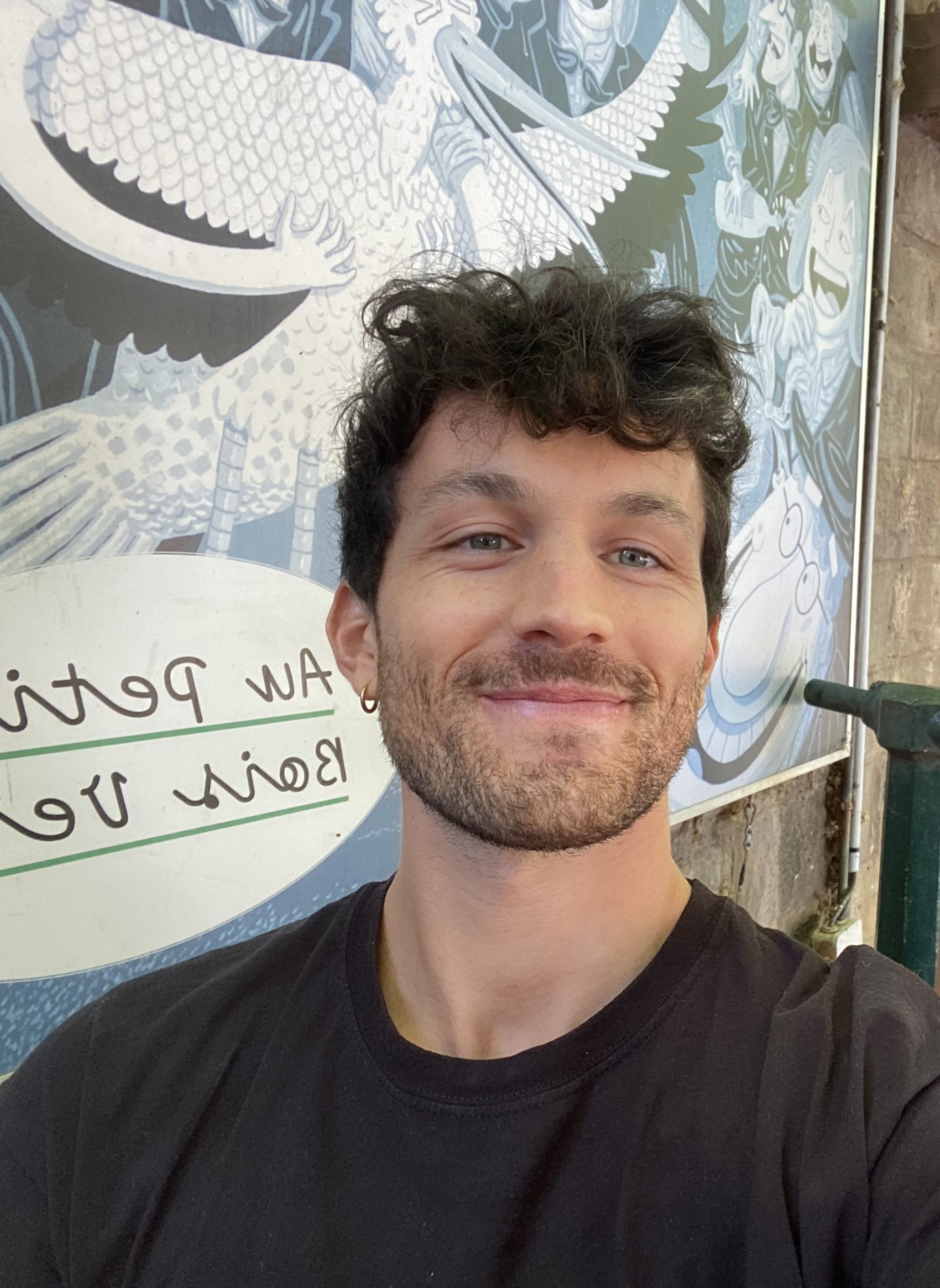 Erwan, smiling, in front of a dragon mural in Paris